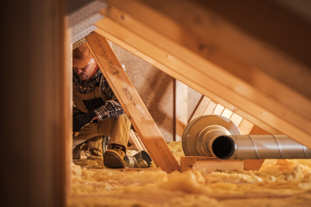 person working in attic on insulation