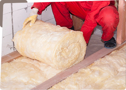 A person in red overalls is laying down insulation.